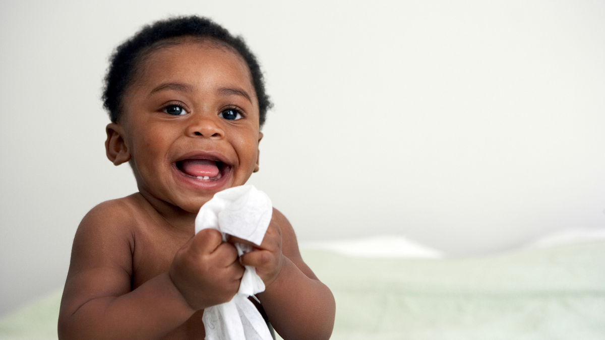 Smiling baby holding a wipe