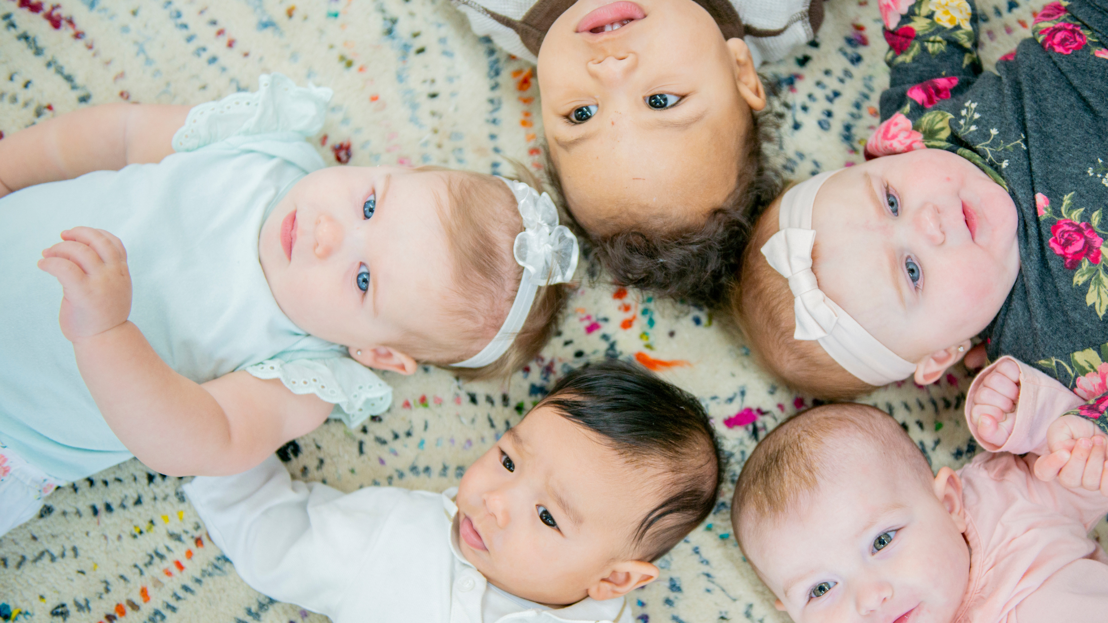 five babies laying face up in a star formation
